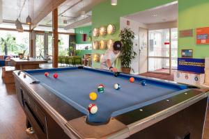 a man playing pool in a room with a pool table at Stayokay Hostel Egmond in Egmond-Binnen