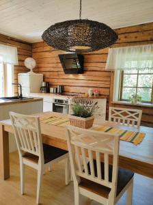una cucina con tavolo in legno e sedie bianche di Hellamaa Retrovisiit Alma & Vilma a Hellamaa
