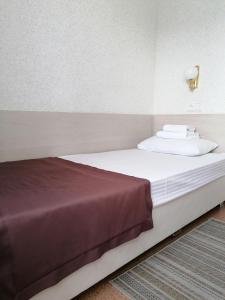 a bed with white sheets and pillows in a room at Hotel Kolos in Barnaul