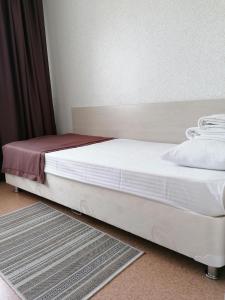 a bed with white sheets and a red blanket at Hotel Kolos in Barnaul