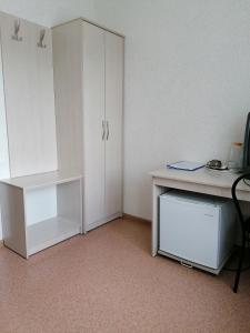 バルナウルにあるHotel Kolosの白いデスクと白いキャビネットが備わる客室です。