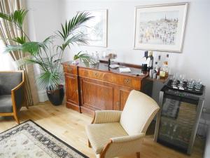 a living room with a wooden cabinet and two chairs at The Redstone Guesthouse in Blackpool