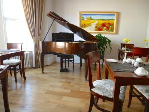 a piano in a living room with a table and chairs at The Redstone Guesthouse in Blackpool +26 photos