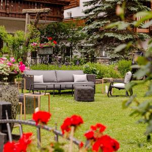 un sofá sentado en un patio con flores rojas en Chesa Valese, en Zermatt