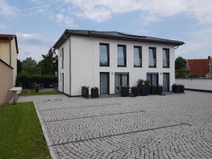 une maison blanche avec une allée en pierre dans l'établissement Glindower Alpen Pension, à Werder