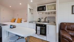 eine kleine weiße Küche mit einem Tisch und einem Sofa in der Unterkunft Tayview Lodges in Dunkeld