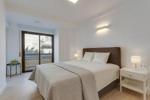 um quarto branco com uma cama e uma janela em La Playa - Alicante City Center em Alicante