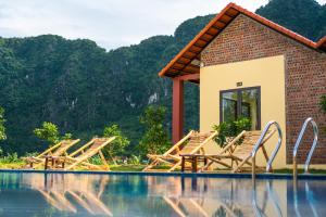 un complejo con una piscina con sillas y montañas de fondo en Trang An Retreat, en Ninh Binh