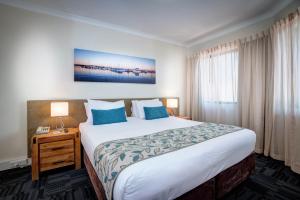 Cette chambre comprend un grand lit avec des oreillers bleus. dans l'établissement Broadwater Resort Como, à Perth 42 autres photos
