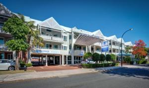 un grand bâtiment blanc avec une rue en face dans l'établissement Broadwater Resort Como, à Perth