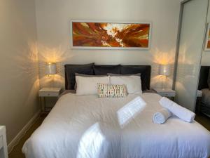 a bedroom with a large white bed with two lamps at Governor Luxe 1 BR Apartment in the heart of Barton WiFi Gym Wine Secure Parking Canberra in Kingston 