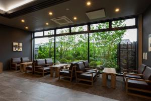 Hotel Route-Inn Yonago في يوناغو: غرفة انتظار مع كراسي وطاولات ونافذة كبيرة