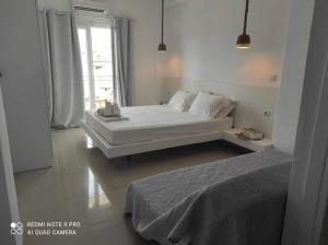 a white bedroom with a bed and a window at Afytos Dream suites sea view in Afitos