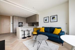 Premium Apartment near Liverpool Street Station في لندن: غرفة معيشة مع أريكة زرقاء ومطبخ