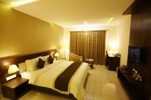 a bedroom with a large bed and a television at WEST FORT HOTEL in Bangalore