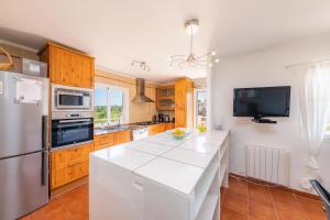 a kitchen with a white counter top and wooden cabinets at Villa Sol in Cala Figuera