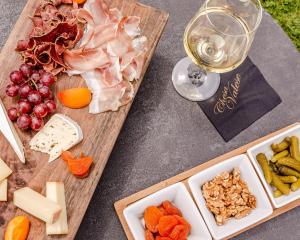 a table with cheese and meats and a glass of wine at Chesa Valese by Sisters Zermatt in Zermatt