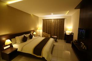 a bedroom with a large bed and a television at WEST FORT HOTEL in Bangalore