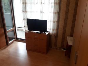 a television on a dresser in front of a window at Удобство in Burgas City