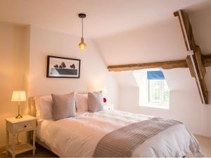 a bedroom with a bed with white sheets and a window at Field View in Cirencester