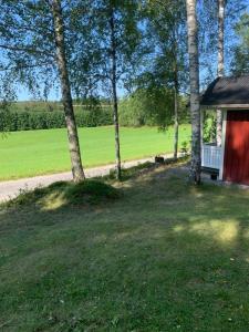 a red house with a tree next to a field at Grindhammaren B&B in Ramsberg