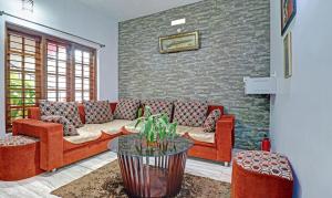 a living room with red couches and a brick wall at Treebo Avyukta Stay in Madikeri