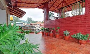 eine Terrasse mit Topfpflanzen und einer roten Ziegelwand in der Unterkunft Treebo Trend Avyukta Stay in Madikeri