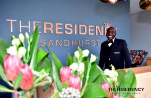 a man in a tuxedo standing next to flowers at The Residency Sandhurst in Johannesburg
