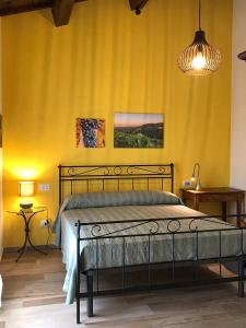 1 dormitorio con cama y pared amarilla en Podere Baratta agriturismo e cantina, en Collinello