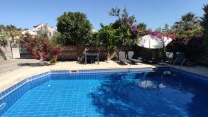 een blauw zwembad met een tafel en een parasol bij Villa Ruby in Fethiye