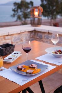 a table with a plate of food and a glass of wine at Margo Beach Hotel in Gythio