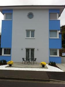 un edificio azul y blanco con 2 sillas delante en Ferienwohnung Viktoria en Bad Kissingen