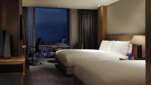 a hotel room with two beds and a window at LOTTE City Hotel Jeju in Jeju