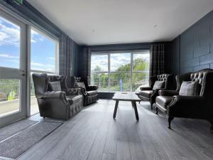 a living room with chairs and a table and windows at Rostrevor Mountain Lodge "Cosy & Friendly" in Rostrevor