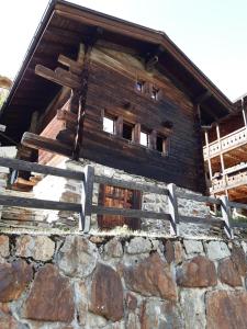 un edificio de madera con ventanas en la parte superior de una pared de piedra en Geburtshaus Prior Siegen, en Blatten