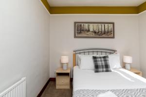 a bedroom with a bed and a nightstand with two lamps at Stunning, Remodelled Cottage, Picturesque Location in Duncanston