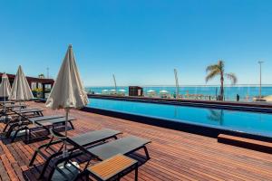 a row of chairs and umbrellas next to a swimming pool at Dom Jose Beach Hotel (Plus) in Quarteira