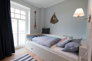 ein Bett mit Kissen darauf in einem Zimmer mit Fenster in der Unterkunft Landhaus Lindenhof, Wohnung Meertied in Wangerooge