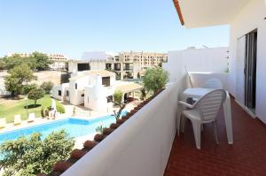 balcón con mesa y sillas y piscina en Apartamentos Pedro for Families by Bedzy, en Albufeira