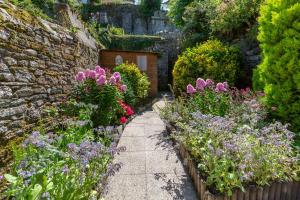 un jardin avec des fleurs et un mur en pierre dans l'établissement El Nido, à Morlaix