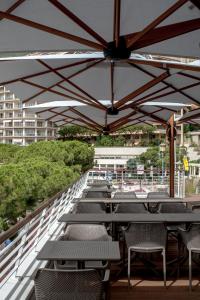 una fila de mesas y sillas bajo una sombrilla en Boutique Hotel Miramar, en Montecarlo