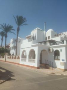 a white building with palm trees in the background at Marrakesh in Los Alcázares +6 photos