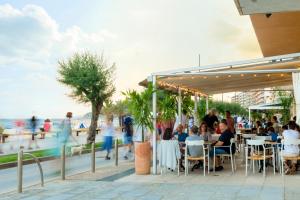 un grupo de personas sentadas en un restaurante cerca de la playa en Hostal Olga en Sant Antoni de Calonge