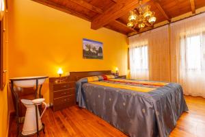 a bedroom with a bed and a table and a chandelier at Vivienda Vacacional Casa Fidel in Campas