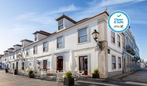 een wit gebouw met tafels en stoelen ervoor bij Pousada Vila Real Santo Antonio in Vila Real de Santo António