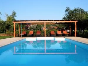 a swimming pool with a gazebo and orange chairs at Verdemar in Cercal
