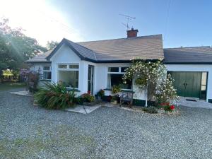 a white house with flowers in front of it at Hawthorn Cottage in Greencastle