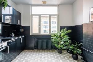 une cuisine avec des armoires noires, une fenêtre et une plante dans l'établissement Smartflats Design - Esplanade, à Bruxelles