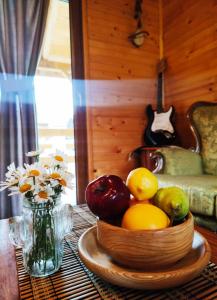 eine Schale Obst auf einem Tisch mit einer Vase Blumen in der Unterkunft Guesthouse MG in Žabljak