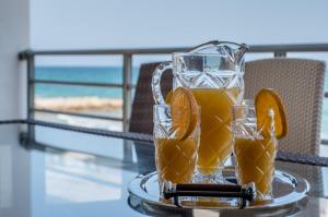 a glass pitcher of orange juice on a glass table at White Crystal Beachfront Apartment in Gournes